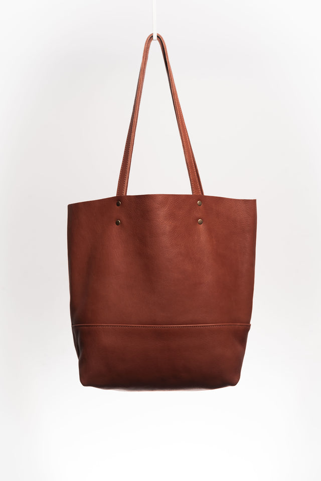 Natural-grained leather unlined tote bag. It features two interior pockets, one zippered, and one open.&nbsp; It comes with fixed leather handles.