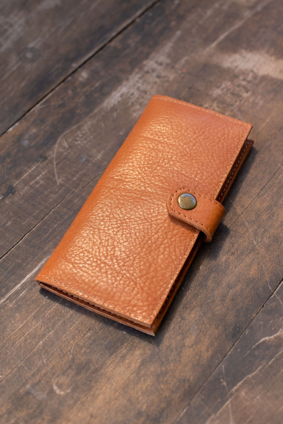 Natural-grained unlined wallet. It features a front snap closure, 8 card slots, 2 bill compartments plus a zippered interior pocket.